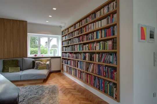 Raumhohe Bibliothekswand mit Leseplatz am Fenster